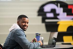 Male student working on laptop in student union